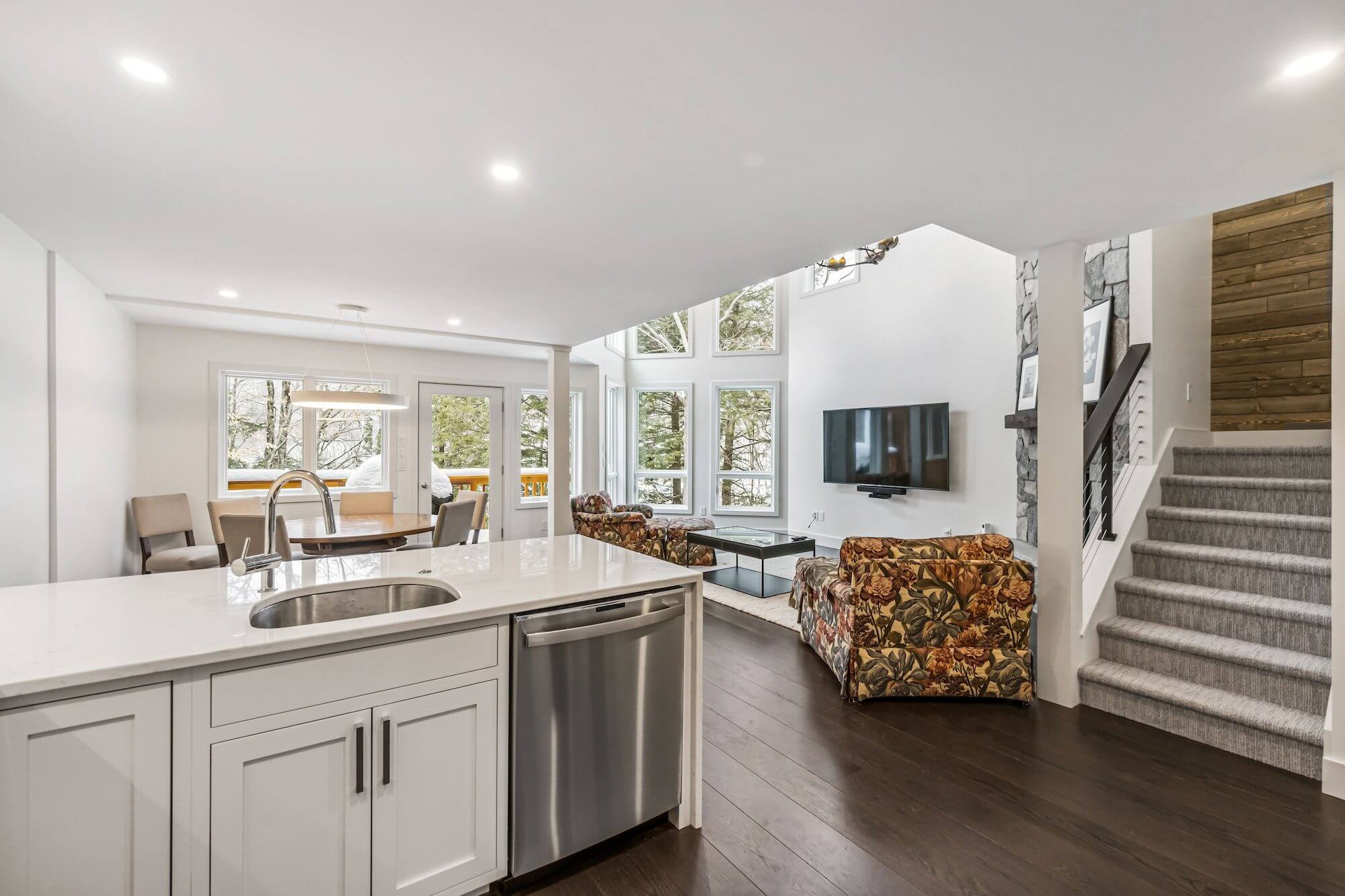 Bright, modern open kitchen and living room with large windows and hardwood floors.