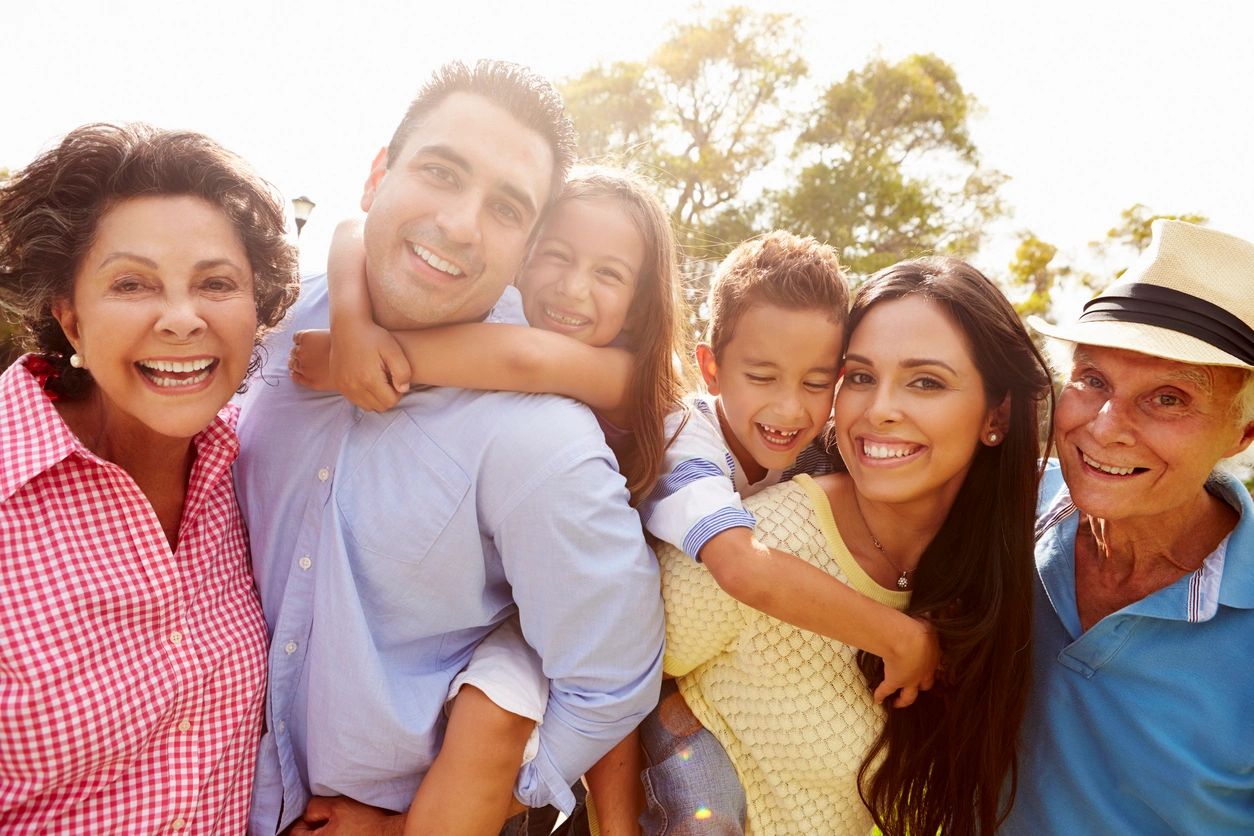 Happy family smiling outdoors in sunlight.